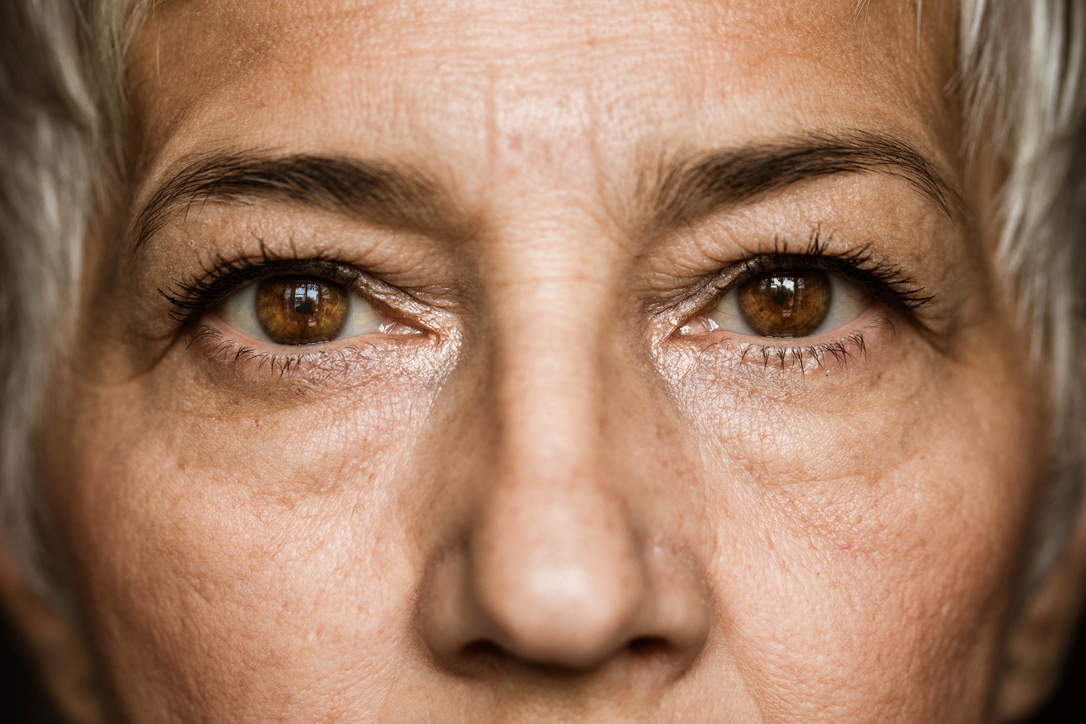 Close up of senior woman's brown eyes looking at camera.